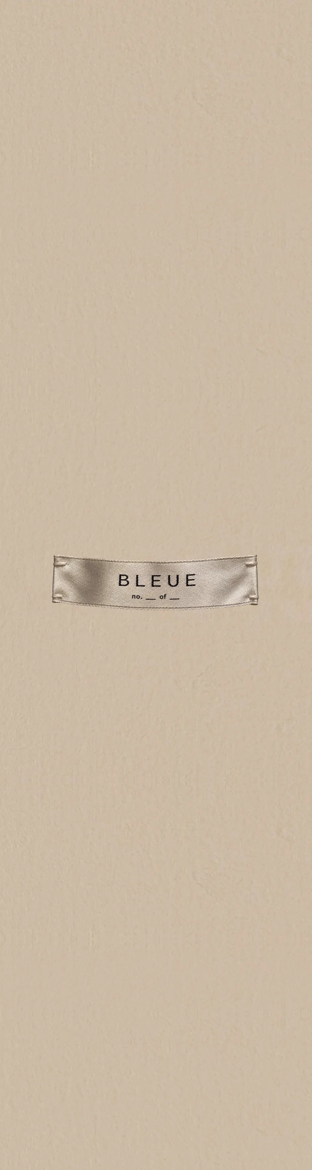 A cream satin BLEUE label printed with no. __ of __, stitched at both ends, on warm beige paper.